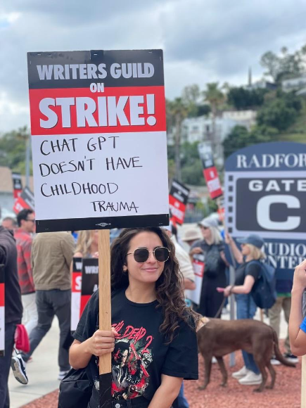 A person holding a demonstration sign reading "Writers guild on STRIKE! ChatGPT doesn’t have Childhood Trauma.”
